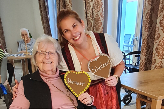 Bensheim: Bewohnerin und Mitarbeiterin in Dirndl mit gebastelten Herzen.